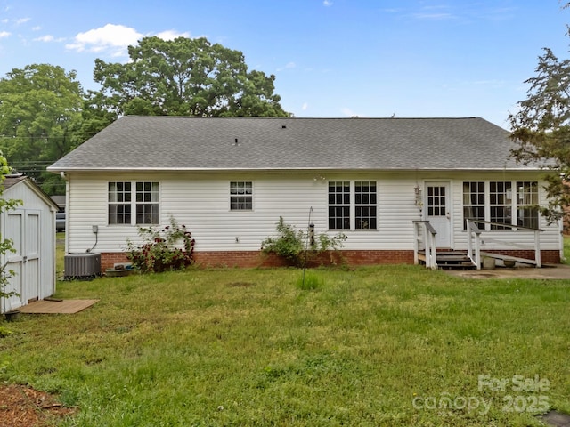 back of house with roof with shingles, a storage unit, a yard, and an outdoor structure