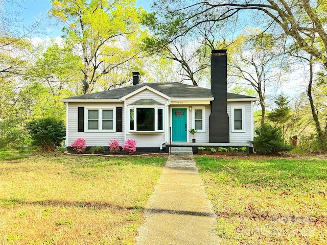 view of front of house featuring a chimney and a front lawn