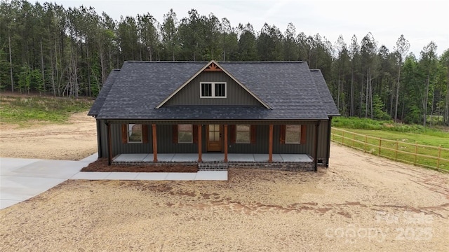 108 Big Hill Rd, Lawndale, NC 28090 - view of front of home with covered porch, a wooded view, fence, roof with shingles, and board and batten siding