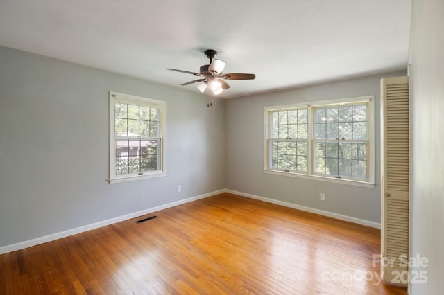 empty room with baseboards, visible vents, ceiling fan, and light wood-type flooring
