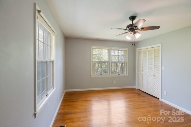 unfurnished bedroom featuring baseboards, ceiling fan, a closet, and wood finished floors