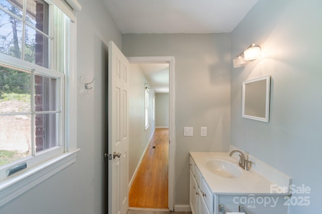 bathroom featuring wood finished floors, baseboards, a wealth of natural light, and vanity