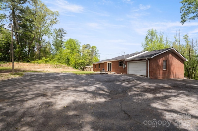 view of front of property with an attached garage, aphalt driveway, and brick siding