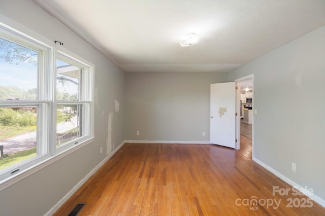 unfurnished room featuring baseboards, light wood finished floors, and visible vents