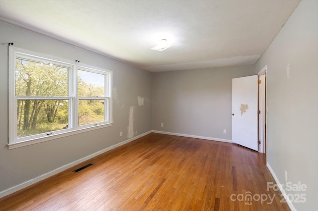 empty room featuring baseboards, visible vents, and light wood finished floors