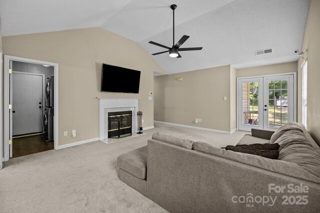 carpeted living area with french doors, a ceiling fan, vaulted ceiling, a high end fireplace, and visible vents