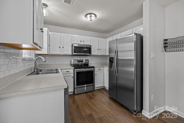 kitchen with a sink, dark wood finished floors, a textured ceiling, and stainless steel appliances