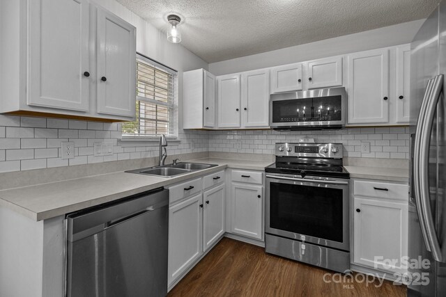 kitchen featuring dark wood-type flooring, a textured ceiling, white cabinetry, a sink, and stainless steel appliances