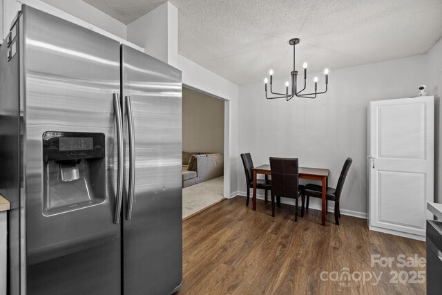kitchen with dark wood-style flooring, baseboards, a textured ceiling, a chandelier, and stainless steel fridge with ice dispenser