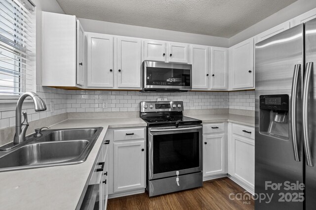 kitchen featuring light countertops, stainless steel appliances, white cabinets, and a sink