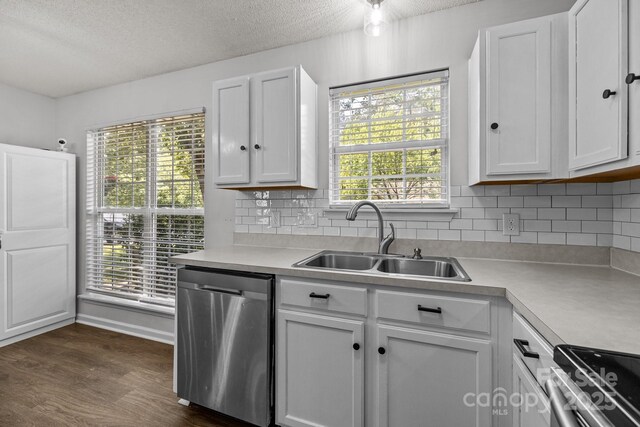 kitchen with appliances with stainless steel finishes, a sink, light countertops, white cabinetry, and backsplash