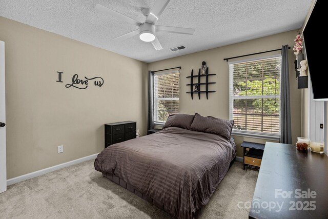 bedroom with a textured ceiling, visible vents, baseboards, and carpet