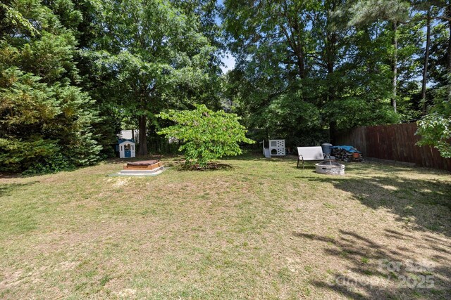 view of yard with fence, a storage unit, an outbuilding, and a fire pit