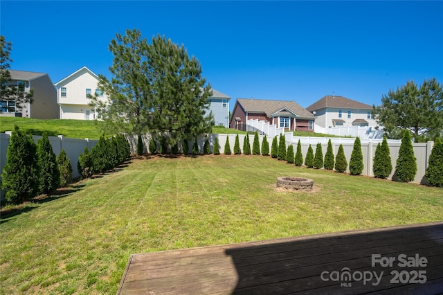 view of yard with a residential view, a fire pit, a fenced backyard, and a wooden deck