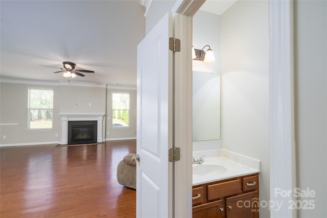 bathroom featuring a fireplace with flush hearth, a ceiling fan, wood finished floors, and a wealth of natural light