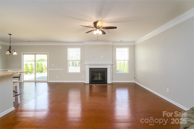unfurnished living room featuring dark wood-type flooring, ornamental molding, a fireplace with flush hearth, and ceiling fan with notable chandelier