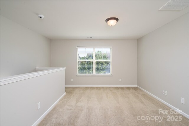 spare room featuring baseboards, light carpet, and visible vents