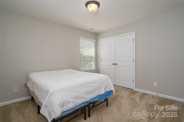 bedroom featuring baseboards, a closet, and light carpet