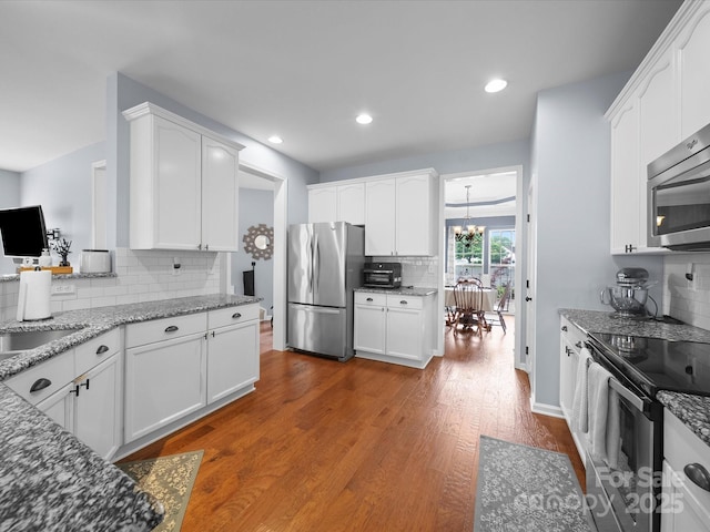 kitchen featuring white cabinets, stainless steel appliances, and backsplash