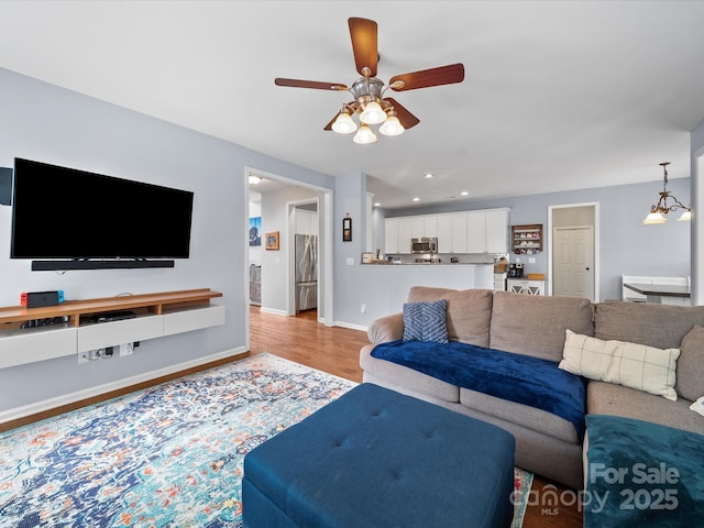 living area with ceiling fan, recessed lighting, light wood-style flooring, and baseboards