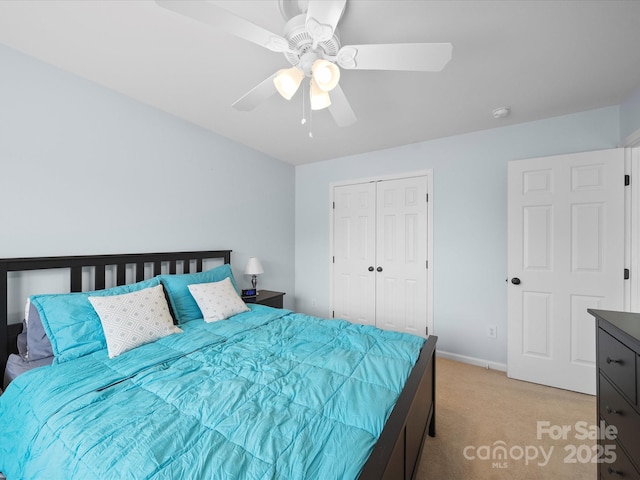 bedroom with ceiling fan, a closet, baseboards, and light carpet
