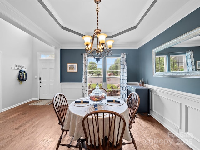 dining room featuring a chandelier, a healthy amount of sunlight, light wood finished floors, and a tray ceiling