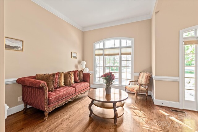 living area with crown molding, baseboards, wood finished floors, and visible vents