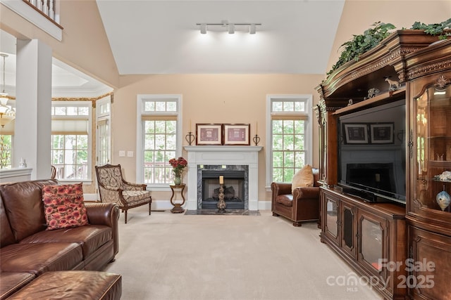 living room featuring baseboards, light colored carpet, rail lighting, vaulted ceiling, and a premium fireplace