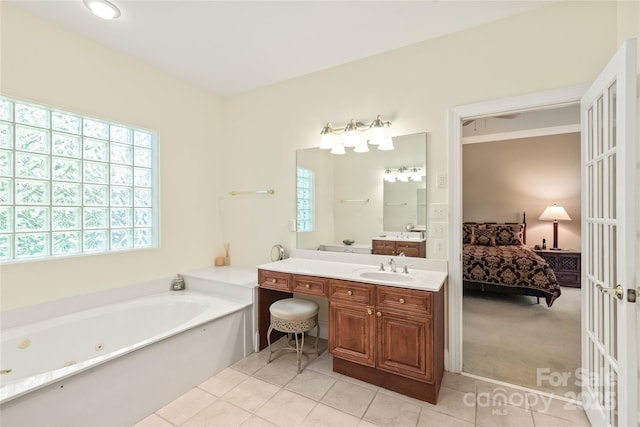ensuite bathroom with a healthy amount of sunlight, vanity, a whirlpool tub, and connected bathroom
