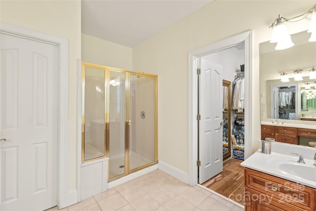 bathroom featuring vanity, baseboards, a stall shower, and a spacious closet