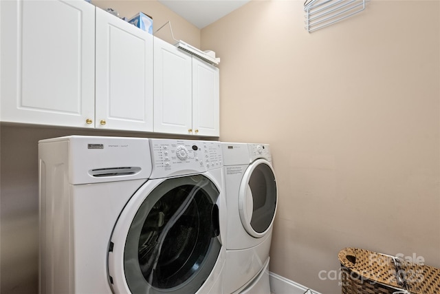 clothes washing area featuring baseboards, cabinet space, and washing machine and dryer