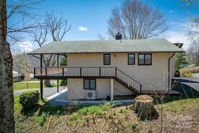 rear view of house featuring roof with shingles, ac unit, a wooden deck, stairway, and a chimney