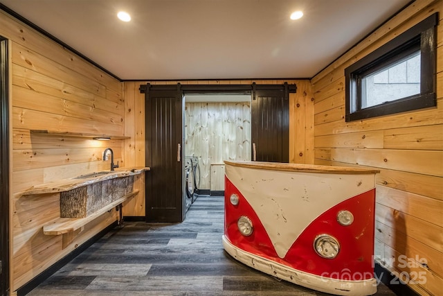 bar with washer and dryer, wooden walls, wet bar, and dark wood-style floors