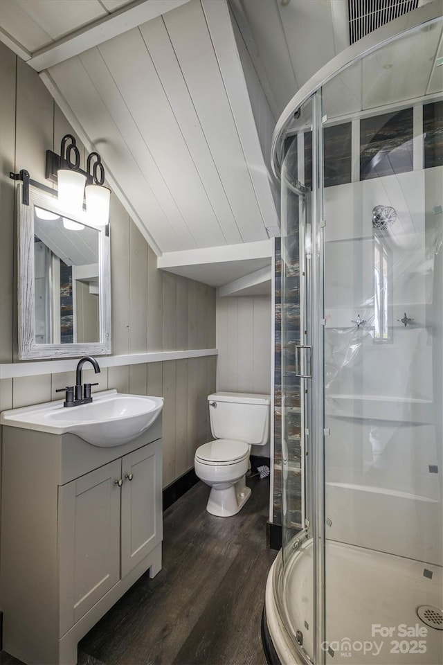 full bath with vanity, wood finished floors, toilet, a stall shower, and vaulted ceiling
