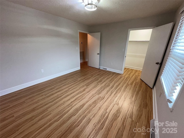 396 Pitts School Rd NW, Concord, NC 28027 - unfurnished bedroom with wood finished floors, a closet, a textured ceiling, and a spacious closet