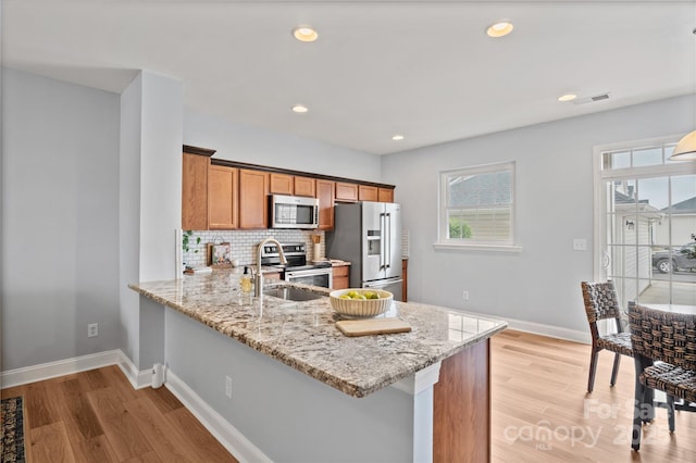 233 E Waterlynn Rd Unit B, Mooresville, NC 28117 - kitchen featuring appliances with stainless steel finishes, brown cabinetry, a peninsula, light stone counters, and recessed lighting