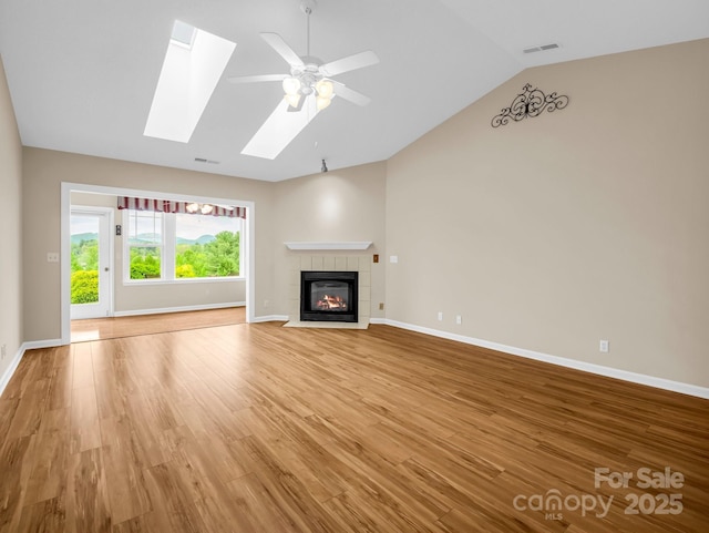 5802 Wood Duck Way, Hendersonville, NC 28792 - unfurnished living room with vaulted ceiling, light wood-type flooring, a tile fireplace, a skylight, and baseboards