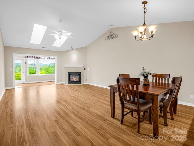 5802 Wood Duck Way, Hendersonville, NC 28792 - dining space with a chandelier, vaulted ceiling, baseboards, light wood-type flooring, and a fireplace