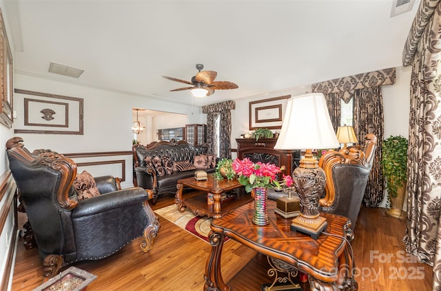 living area with ceiling fan, visible vents, wainscoting, and wood finished floors