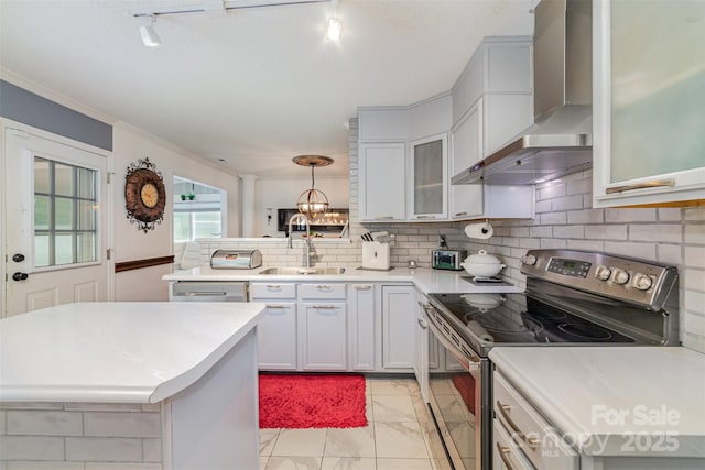 kitchen with marble finish floor, light countertops, wall chimney exhaust hood, a sink, and stainless steel electric range oven
