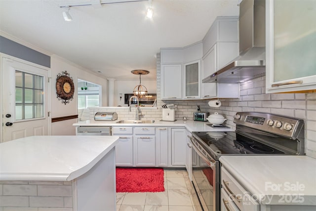 kitchen with stainless steel electric range, a sink, light countertops, marble finish floor, and wall chimney exhaust hood