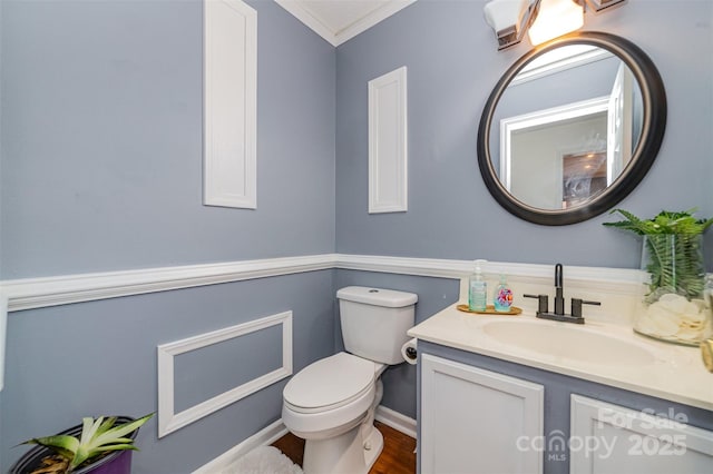 half bath with vanity, crown molding, wood finished floors, and toilet