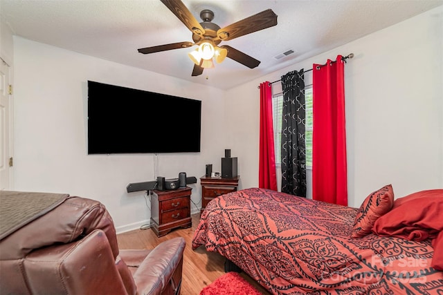 bedroom with baseboards, a ceiling fan, wood finished floors, and visible vents