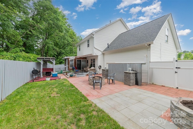 back of property featuring roof with shingles, a fenced backyard, an outdoor fire pit, and a patio area