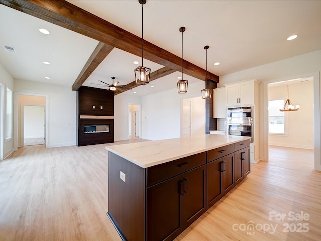 1706 Ruben Rd, Monroe, NC 28112 - kitchen featuring beamed ceiling, a fireplace, light wood finished floors, and double oven