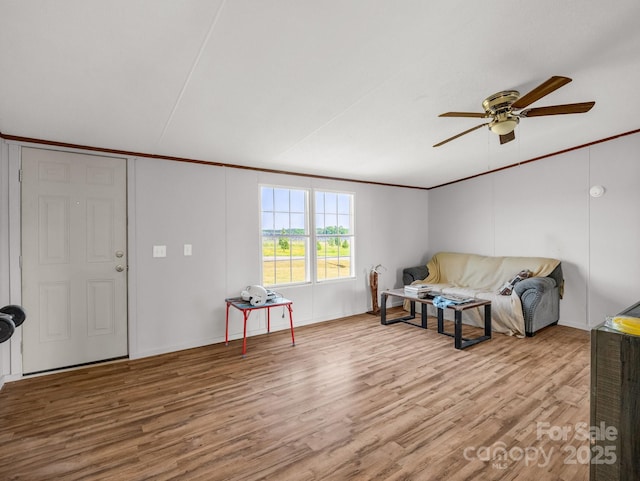 living area with crown molding, baseboards, ceiling fan, and wood finished floors