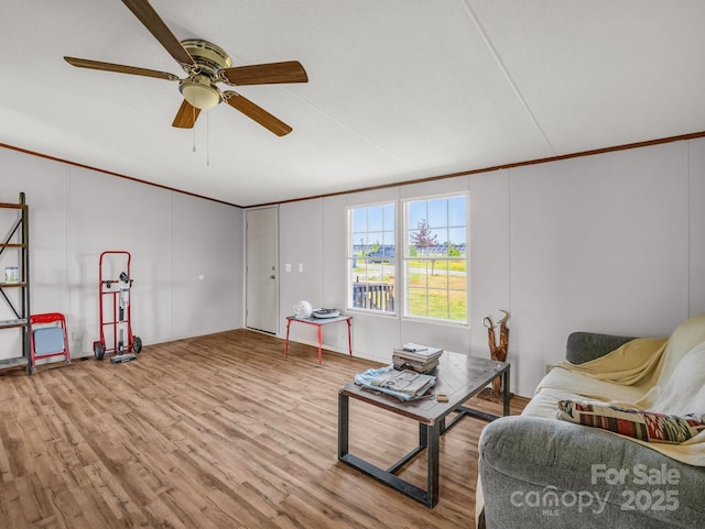 living room featuring crown molding, ceiling fan, a decorative wall, and wood finished floors