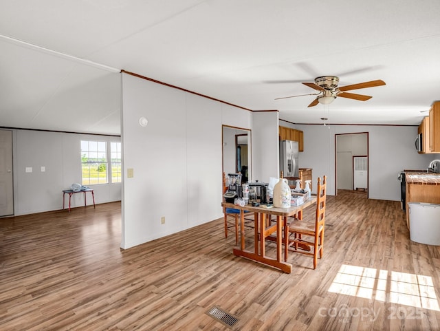 dining room with ceiling fan, light wood finished floors, and visible vents