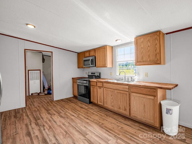 kitchen with stainless steel appliances, a sink, and light wood-style flooring