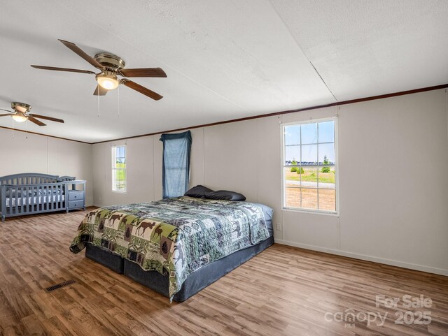bedroom featuring crown molding, baseboards, ceiling fan, and wood finished floors